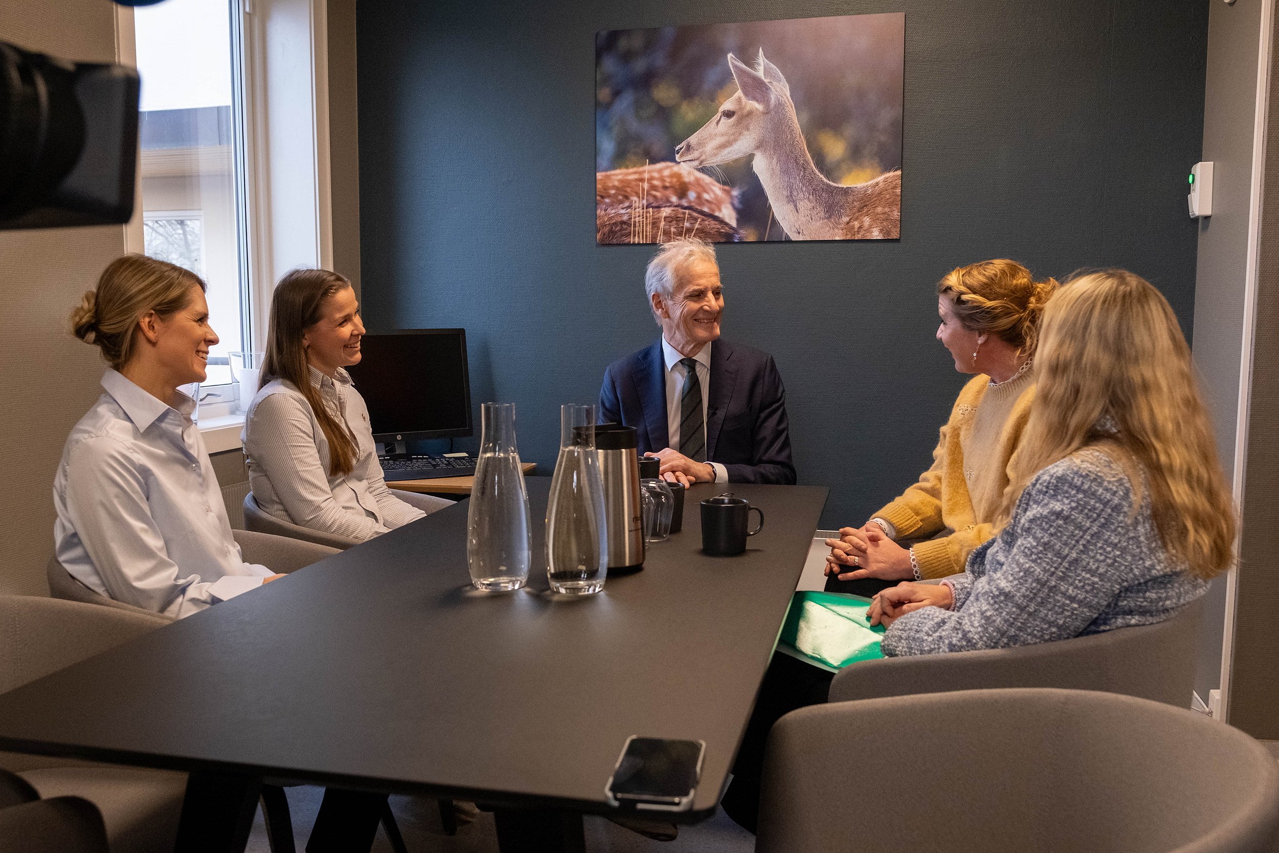 Statsminister Jonas Gahr Støre sitter ved et rundt bord og prater med legene på legesenteret.