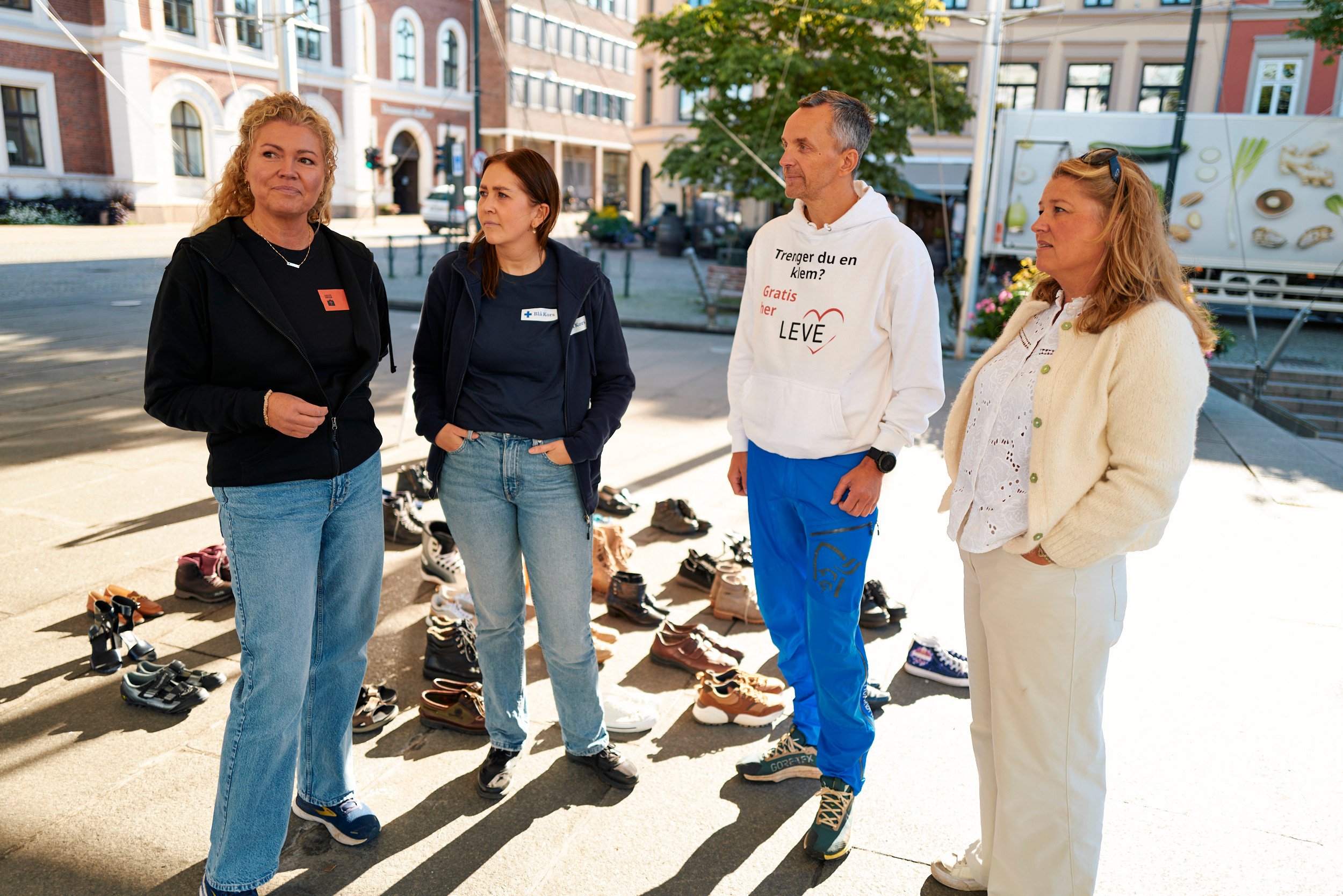 En mann og tre damer står og prater på torgscen. 