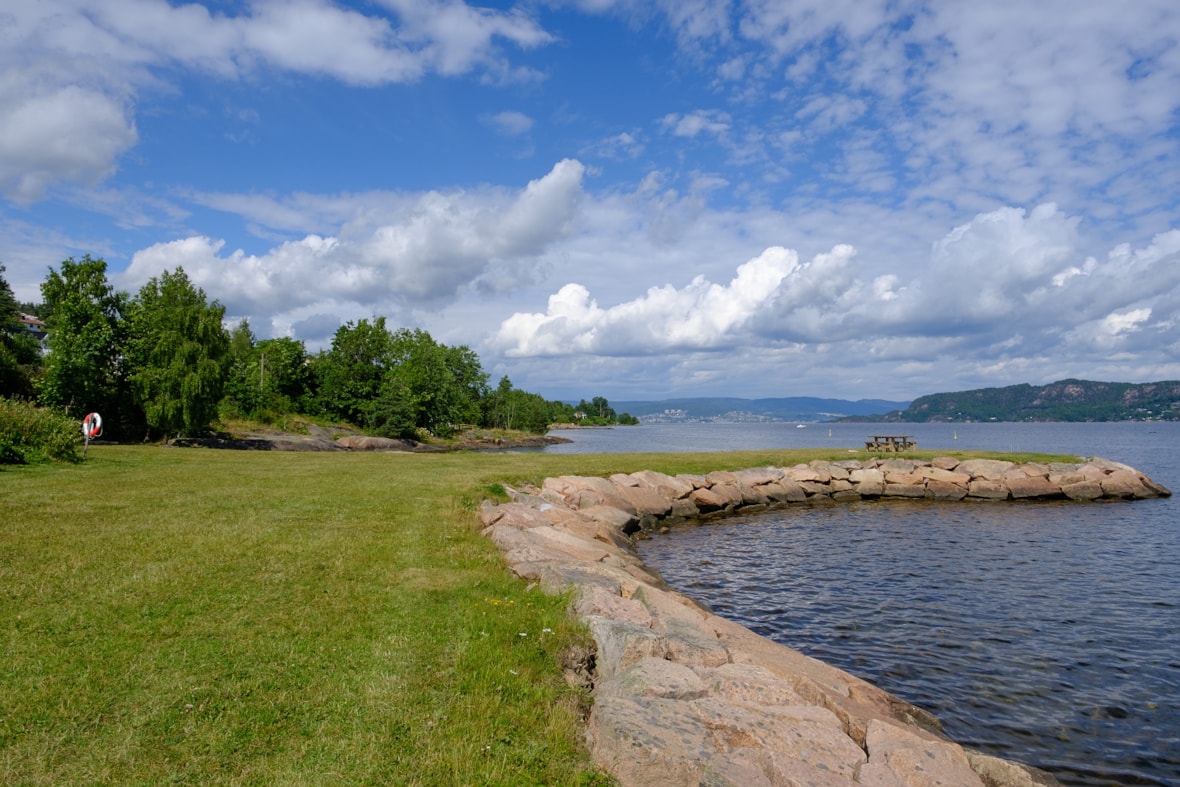 Gressplen, fjord og steinmolo.